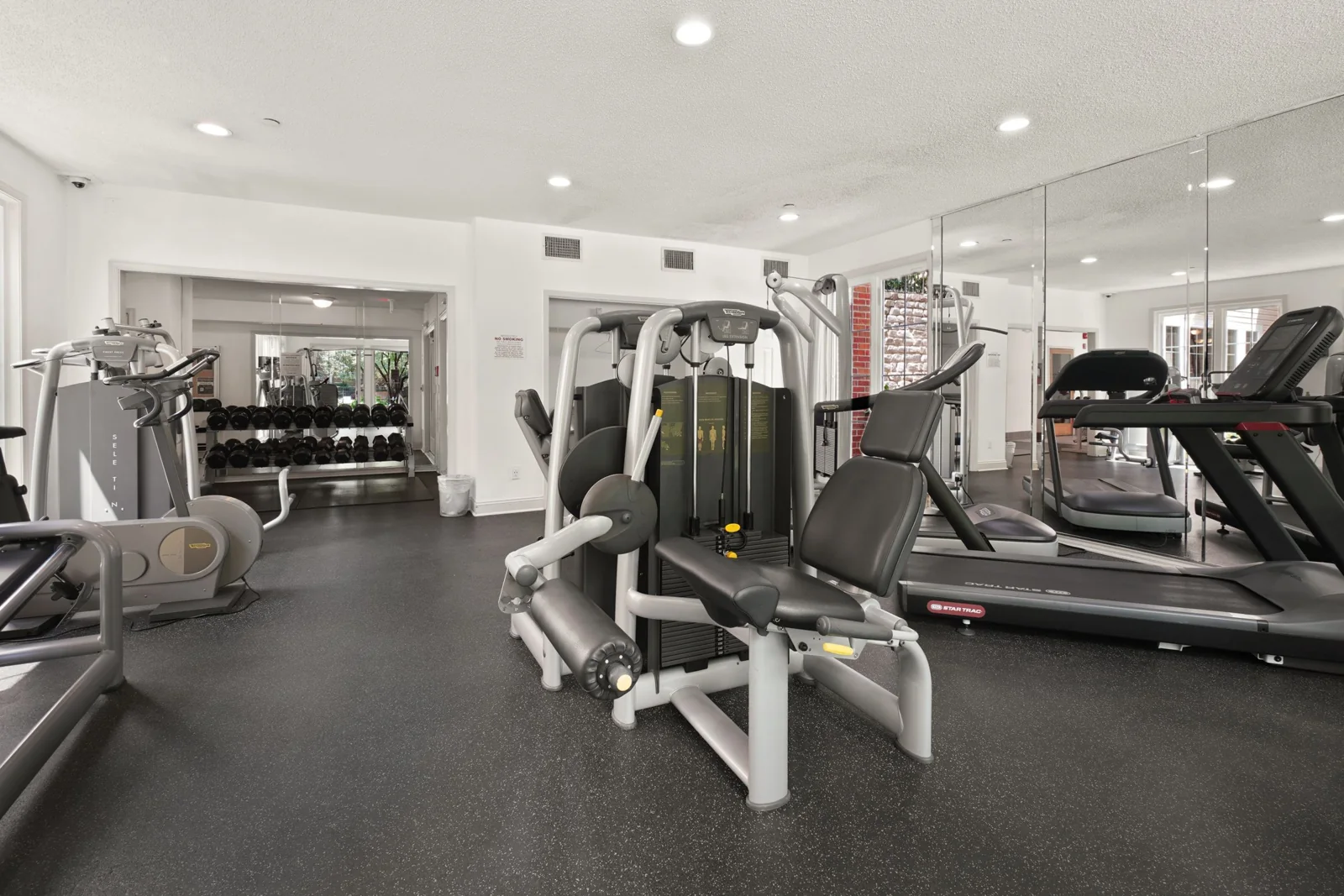 A tidy gym with exercise equipment arranged across the floor